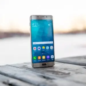 Samsung smartphone placed on a wooden surface outdoors during sunset.
