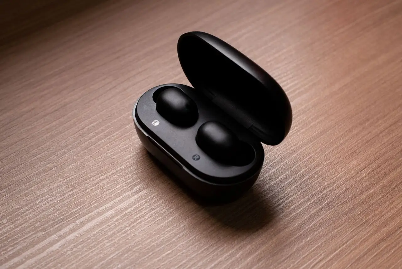 Stylish black wireless earbuds displayed in an open charging case atop a wooden table.