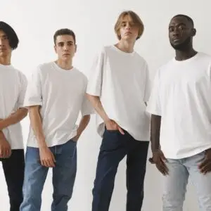 A group of four diverse men modeling white t-shirts and jeans in a studio setting.